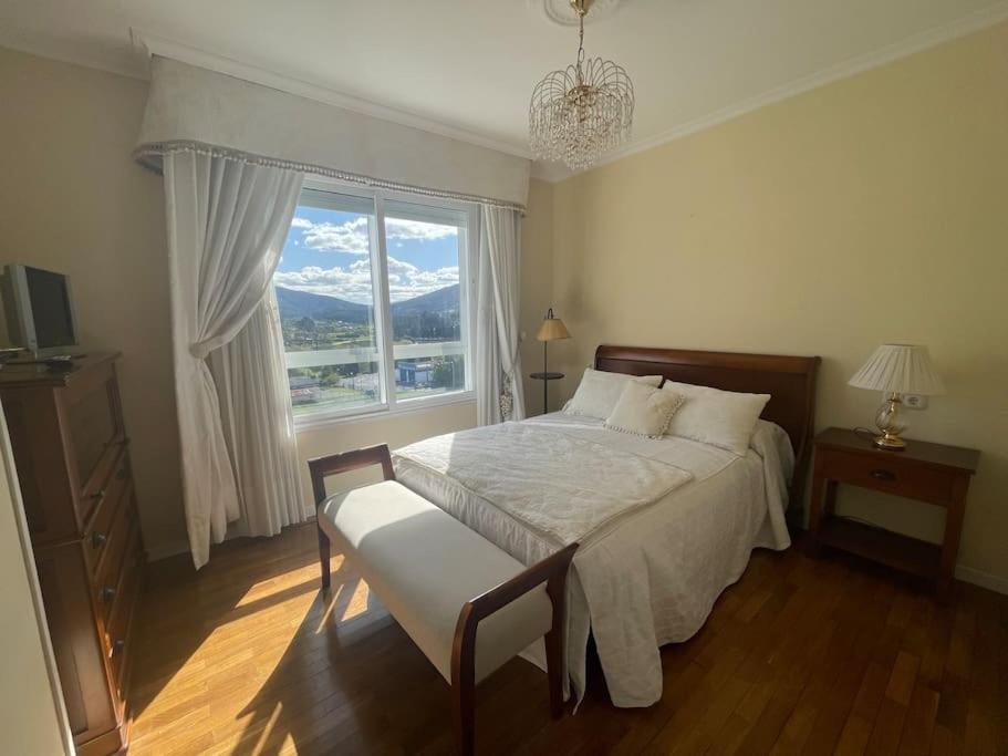 a bedroom with a bed and a large window at Piso vacacional con terraza panorámica a la ría. in Viveiro