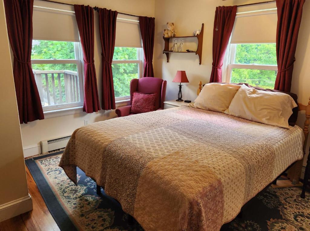 um quarto com uma cama, uma cadeira e janelas em The Morrison House Bed and Breakfast em Somerville