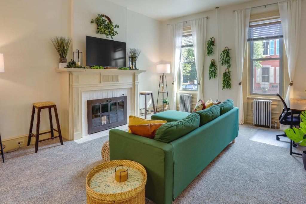 a living room with a green couch and a fireplace at Darling Pennsylvania Vacation Rental with Porch! in Pottstown