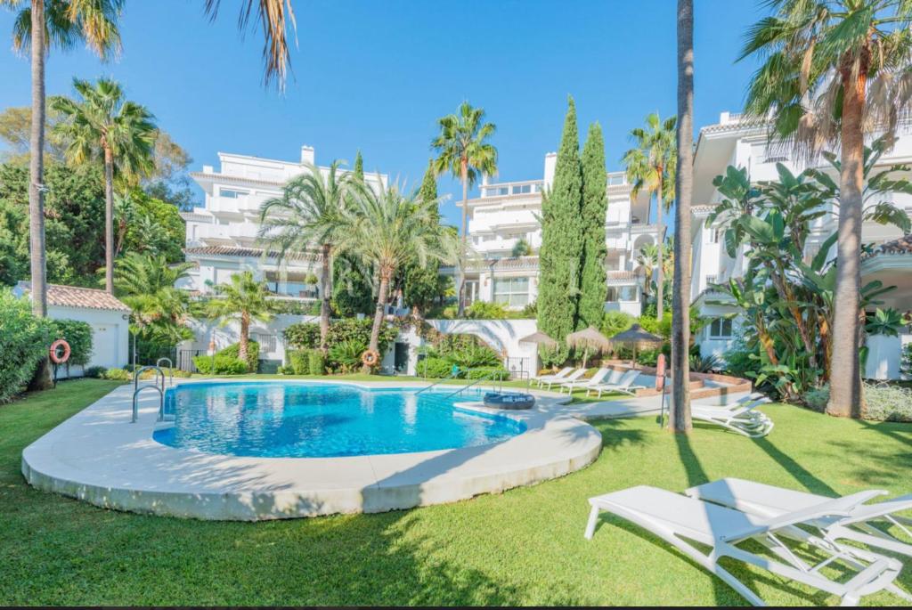 a swimming pool in a yard with palm trees and a building at Apartment in Marbella Golden Mile in Marbella
