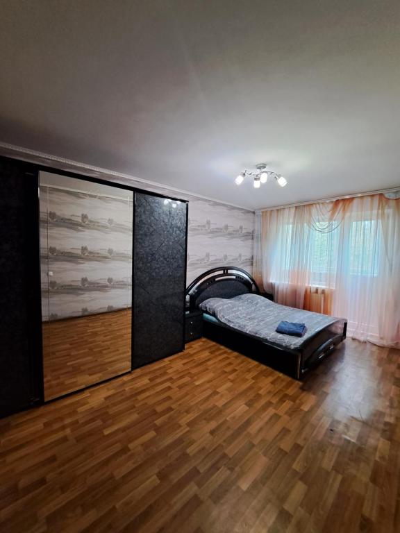 um quarto com uma cama e piso em madeira em Трёхкомнатные апартаменты em Krivoy Rog