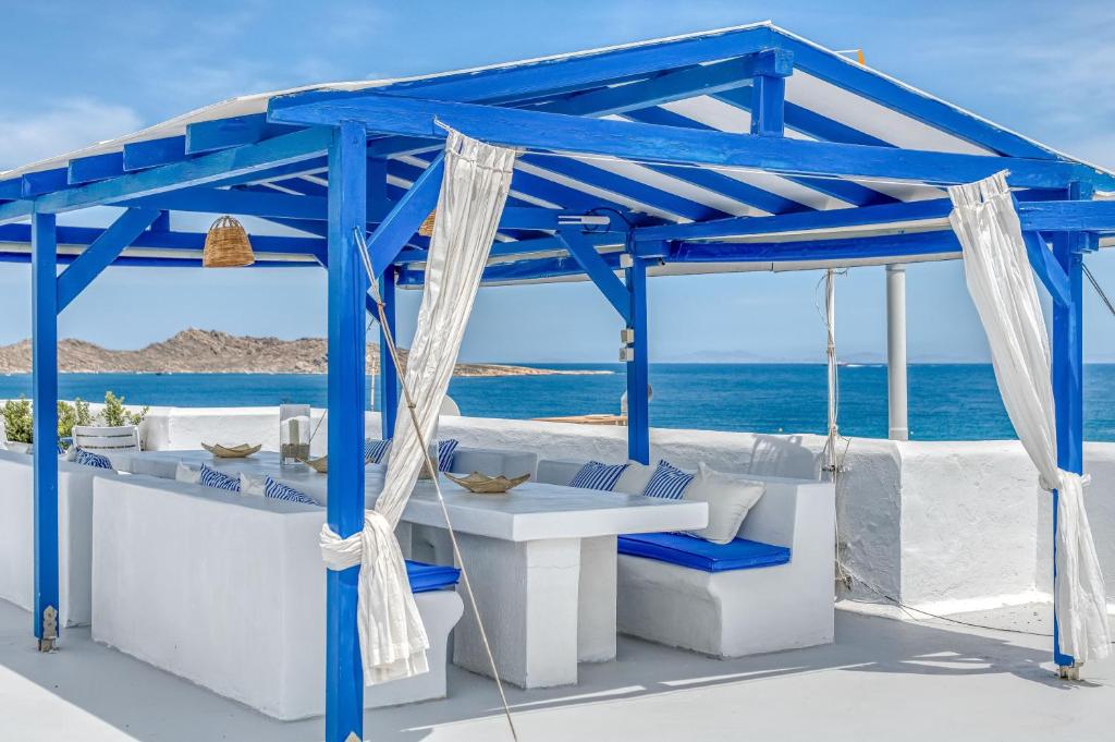 a blue gazebo on the beach with the ocean at Alpha Studios in Naousa