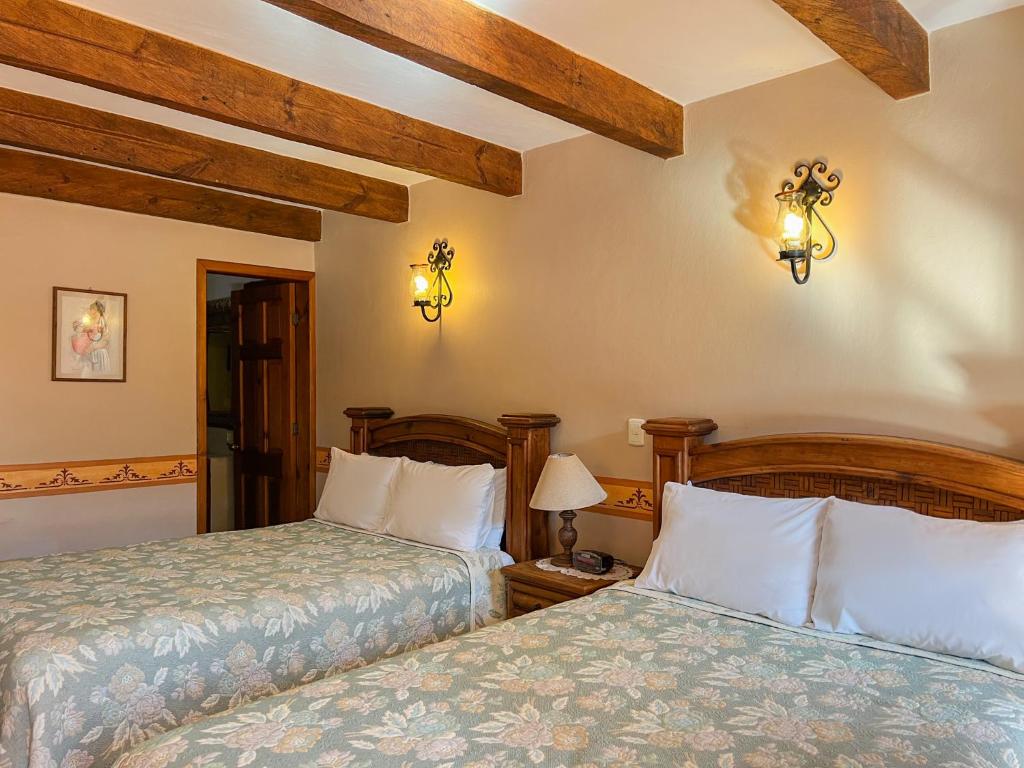 - 2 lits dans une chambre dotée de poutres apparentes dans l'établissement Hotel La Casa de Mamá, à San Cristóbal de Las Casas