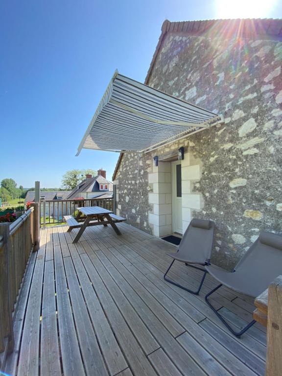 a patio with two chairs and a picnic table on a deck at Gîte Les Mariniers - 3 étoiles in Mareuil-sur-Cher