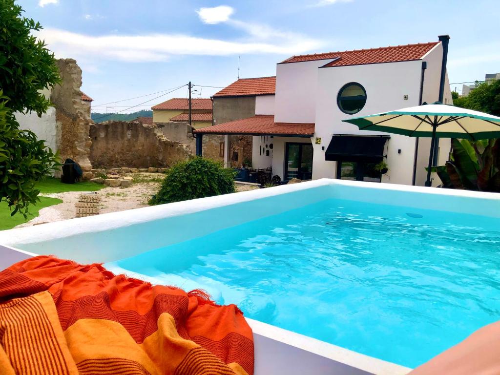 una piscina frente a una casa con sombrilla en Pool oasis with private parking -Vigia 8, en Torres Vedras