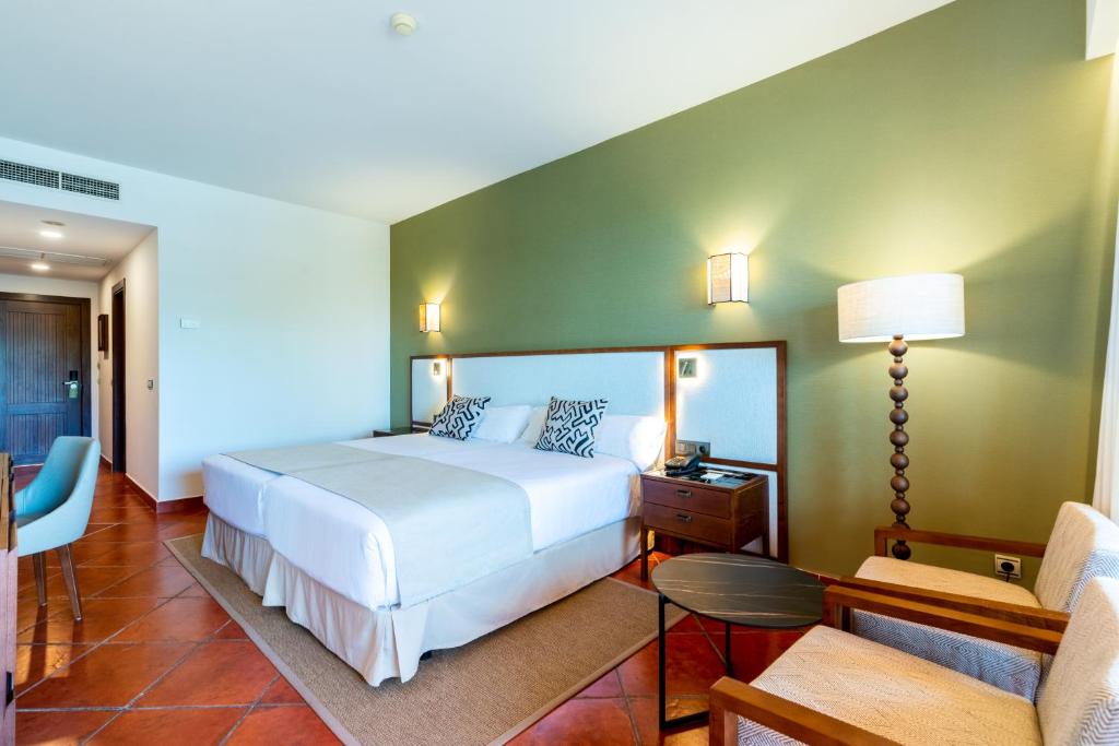 a bedroom with a white bed and a green wall at Puerto Antilla Grand Hotel in Islantilla