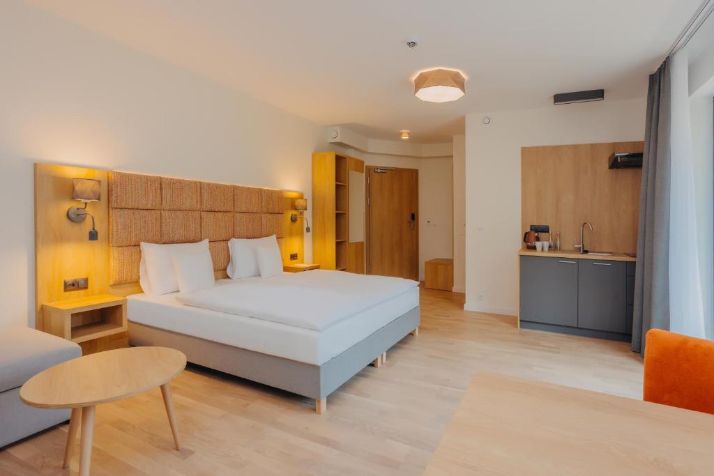 a bedroom with a white bed and a kitchen at Platinum Apartments in Szklarska Poręba