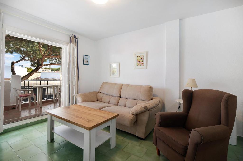 a living room with a couch and a table and a chair at Apartamento primera línea in Chiclana de la Frontera