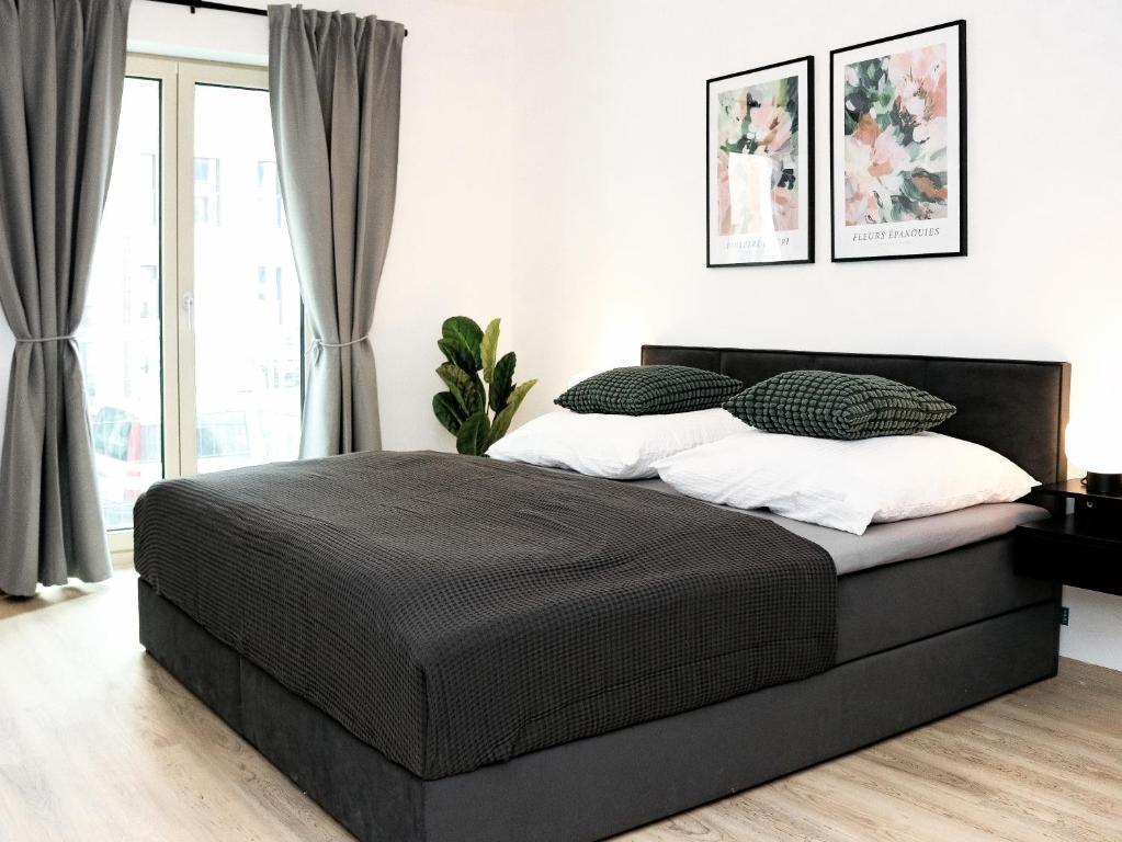 ein Schlafzimmer mit einem schwarzen Bett und einem Fenster in der Unterkunft LIGHTPLACE • Design • Boxspring • Balkon • 2 Smart TV •Innenstadt in Braunschweig