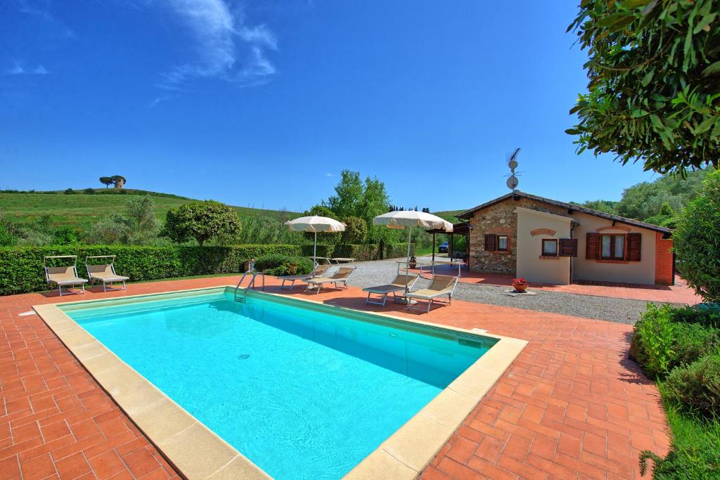 einen Pool mit Stühlen und ein Haus in der Unterkunft Cuccardino by PosarelliVillas in Bibbona