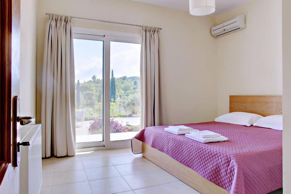 a bedroom with a bed and a large window at Poulades Villa, Corfu in Danilia