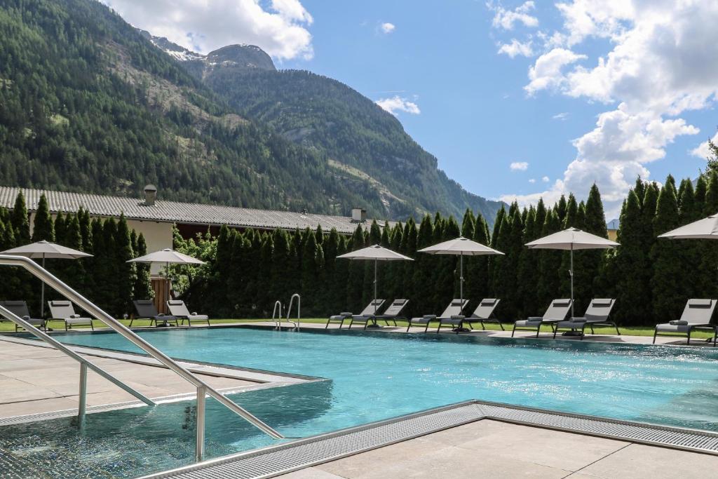a large swimming pool with chairs and umbrellas at Hotel Traube in Pfunds