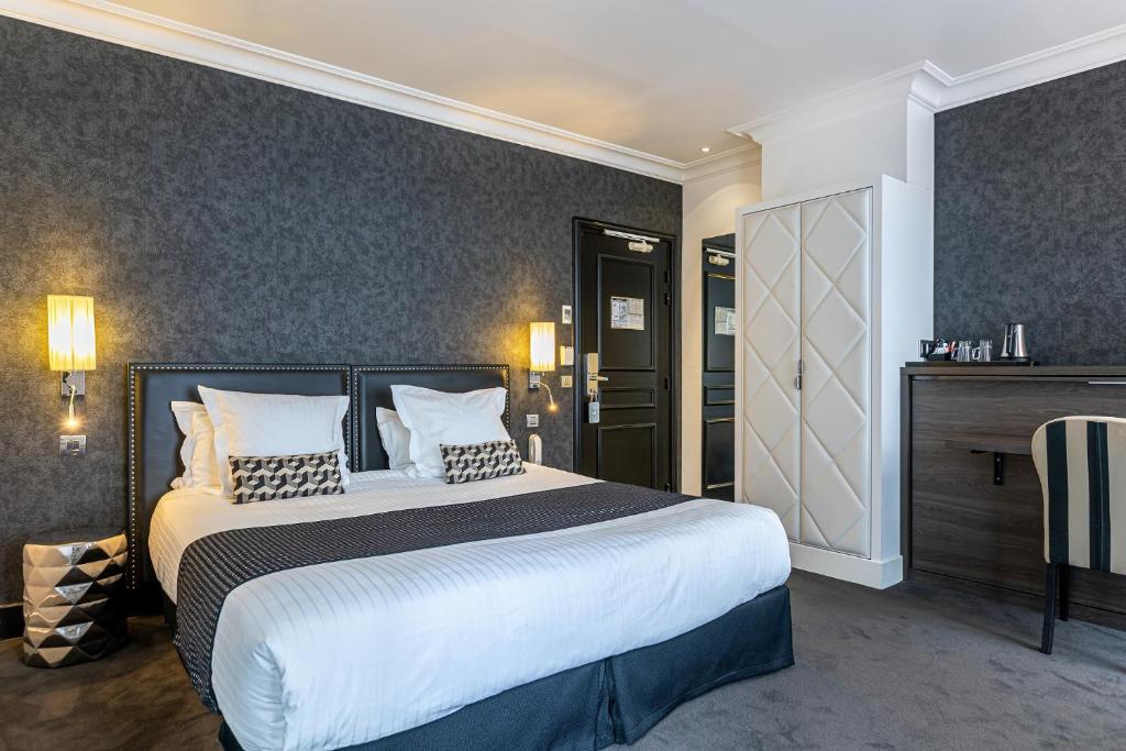 1 dormitorio con 1 cama grande con sábanas y almohadas blancas en Hôtel Diva Opera, en París