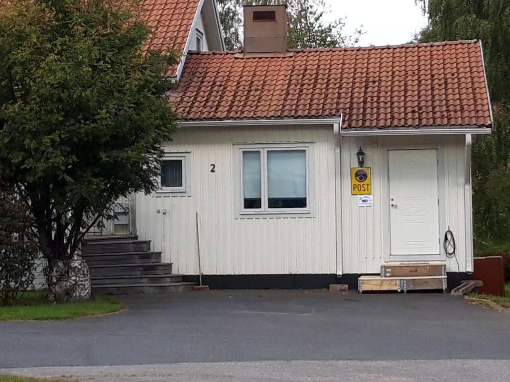 a small white house with a white door and stairs at Old Post Office now cosy apartment close to nature in Hedenäset