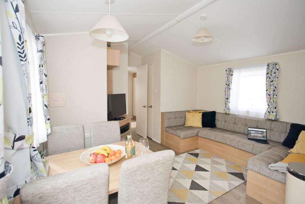 a living room with a table and chairs and a couch at Luxury holiday retreat set within Oakdene Forest - Park activities pass included free! in Saint Leonards