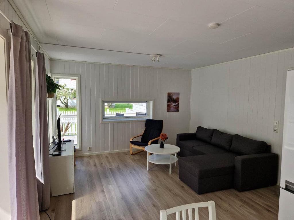 a living room with a black couch and a table at Hillegård in Lærdalsøyri