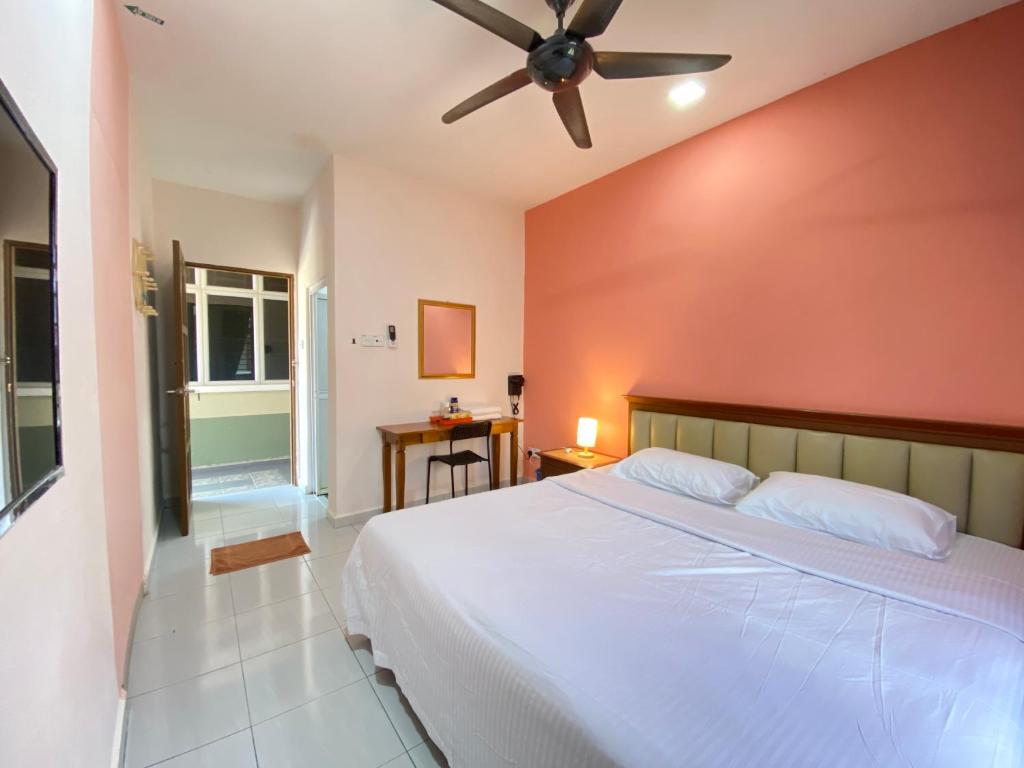 a bedroom with a white bed and a ceiling fan at Besut Guesthouse in Kuala Besut