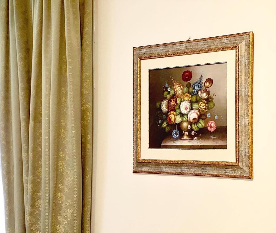 a painting of a vase of flowers next to a curtain at Biagetti Bedrooms Affittacamere in Santa Maria degli Angeli