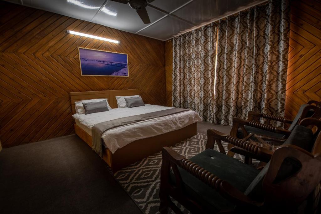 ein Schlafzimmer mit einem Bett in einem Zimmer mit Holzwänden in der Unterkunft Sultan's Guest House in Skardu