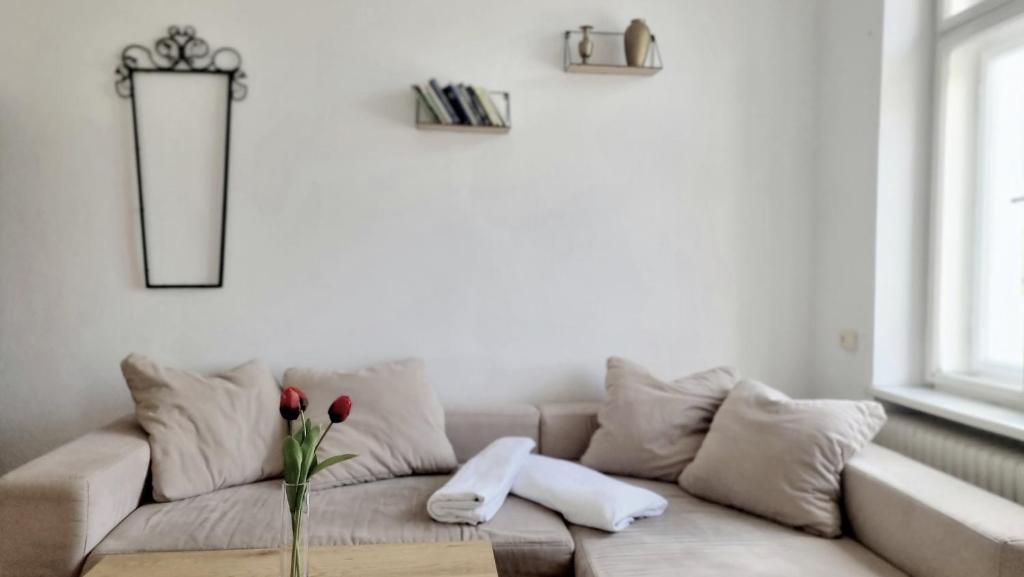 ein weißes Wohnzimmer mit einem Sofa und einer Vase mit Blumen in der Unterkunft Schöne einfache Wohnung in Jugendstilhaus in Feistritz an der Drau