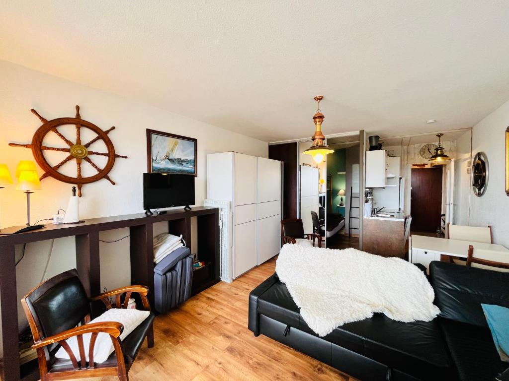 sala de estar con sofá negro y cocina en Appartement du marin art & océan, en Saint-Jean-de-Monts