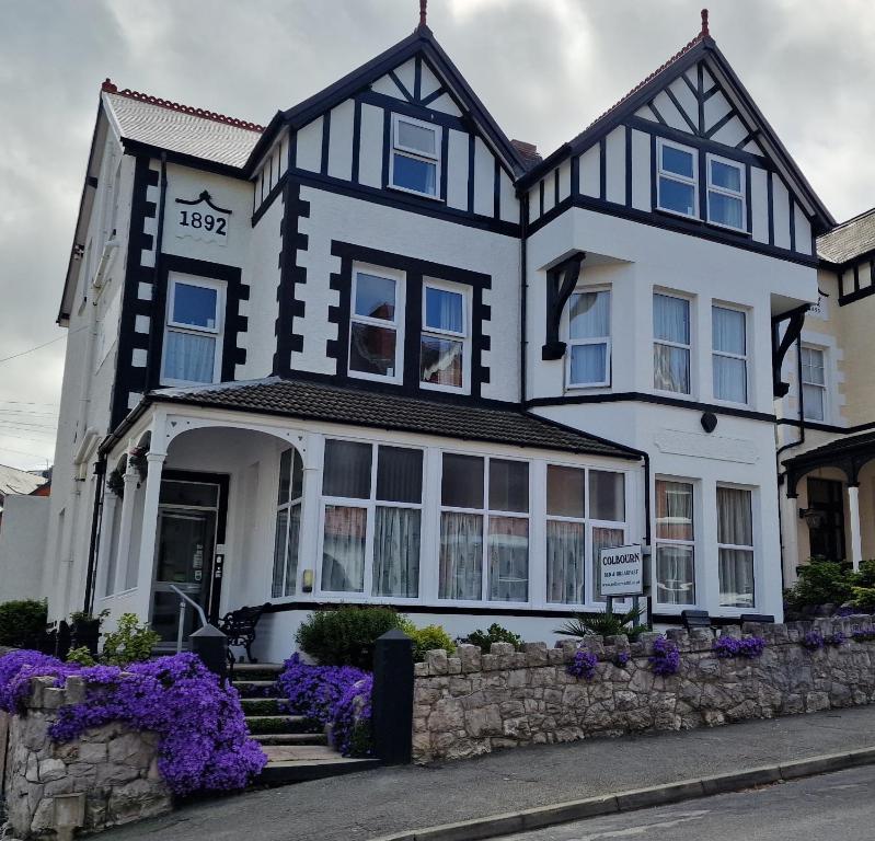 a black and white house with purple flowers in front of it at Colbourn Bed and Breakfast in Colwyn Bay
