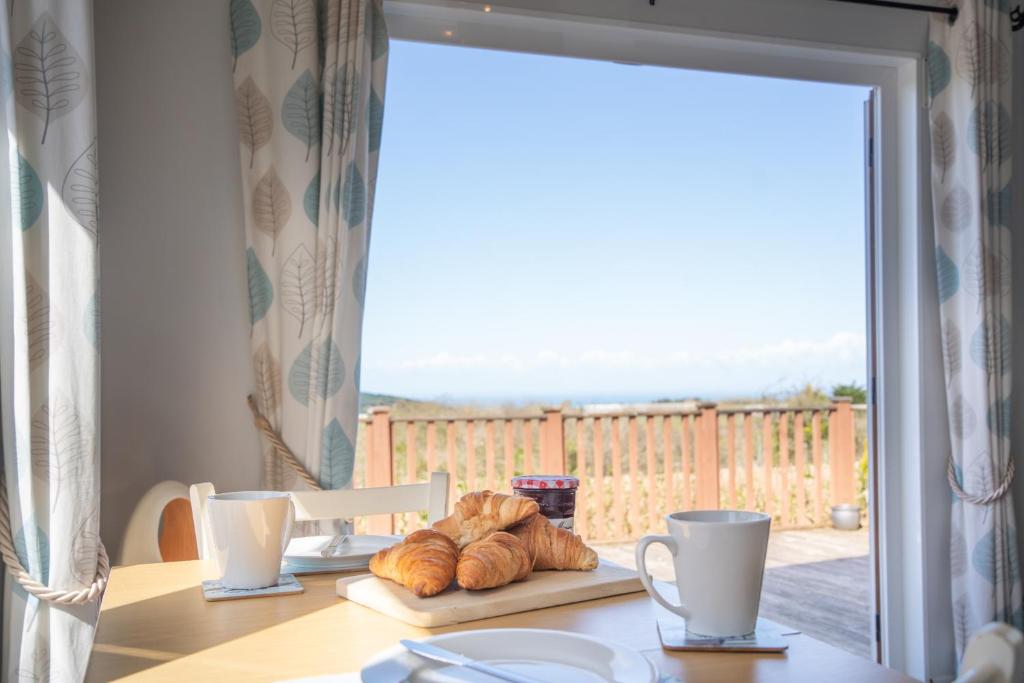a table with croissants and cups and a window with a view at 4 Meadow View in West Down