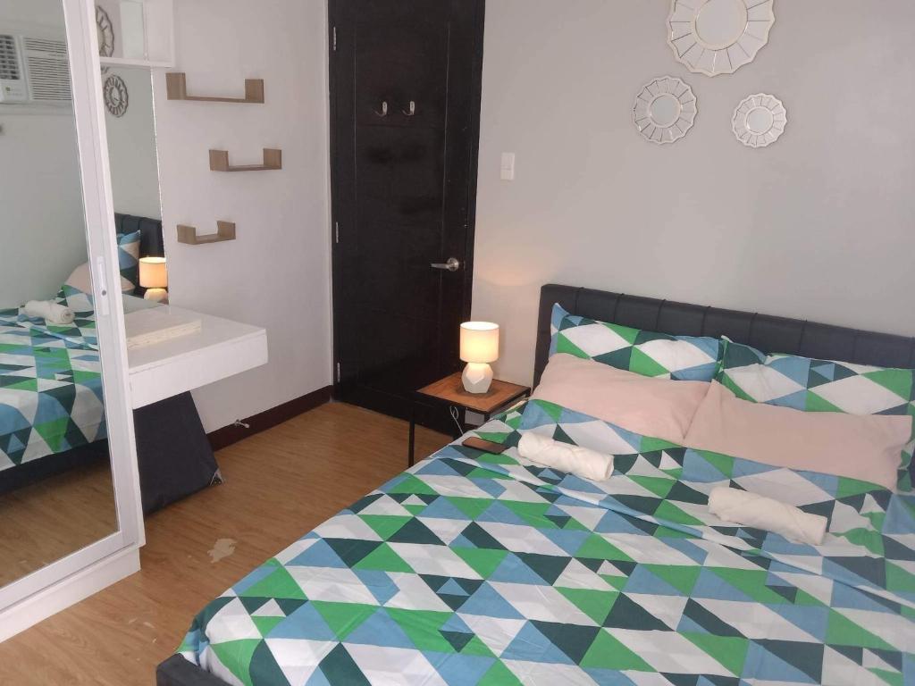 Schlafzimmer mit einem Bett und einem Spiegel in der Unterkunft Mesaverte Residences T2-8H in Cagayan de Oro