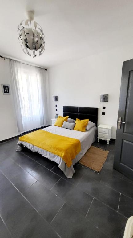 Un dormitorio con una cama con sábanas amarillas y una lámpara de araña. en Le cœur de Marseille 2, en Marsella