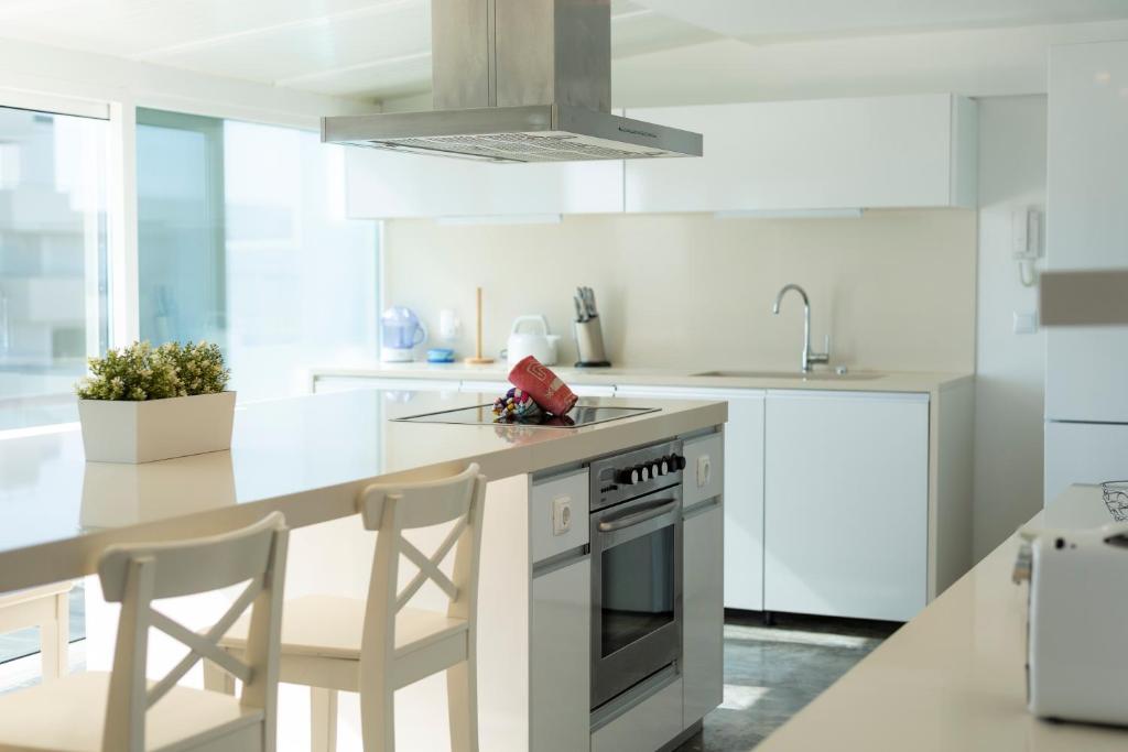 una cocina blanca con armarios blancos y una isla de cocina con sillas en Marina Vilamoura Triplex, en Vilamoura