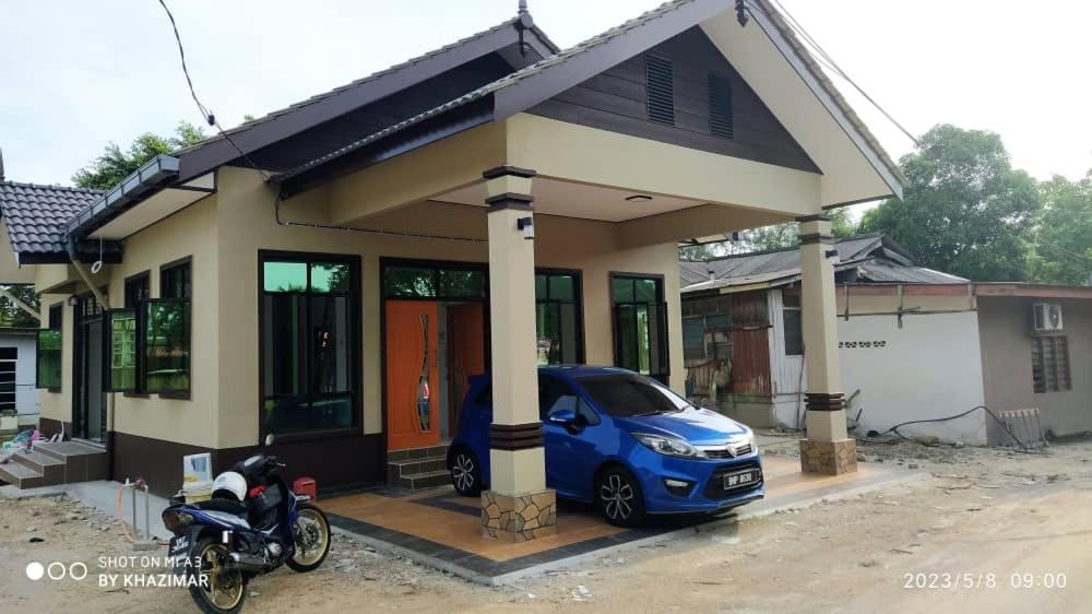 a small blue car parked in front of a house at MAA HOMESTAY BATU BURUK in Kuala Terengganu