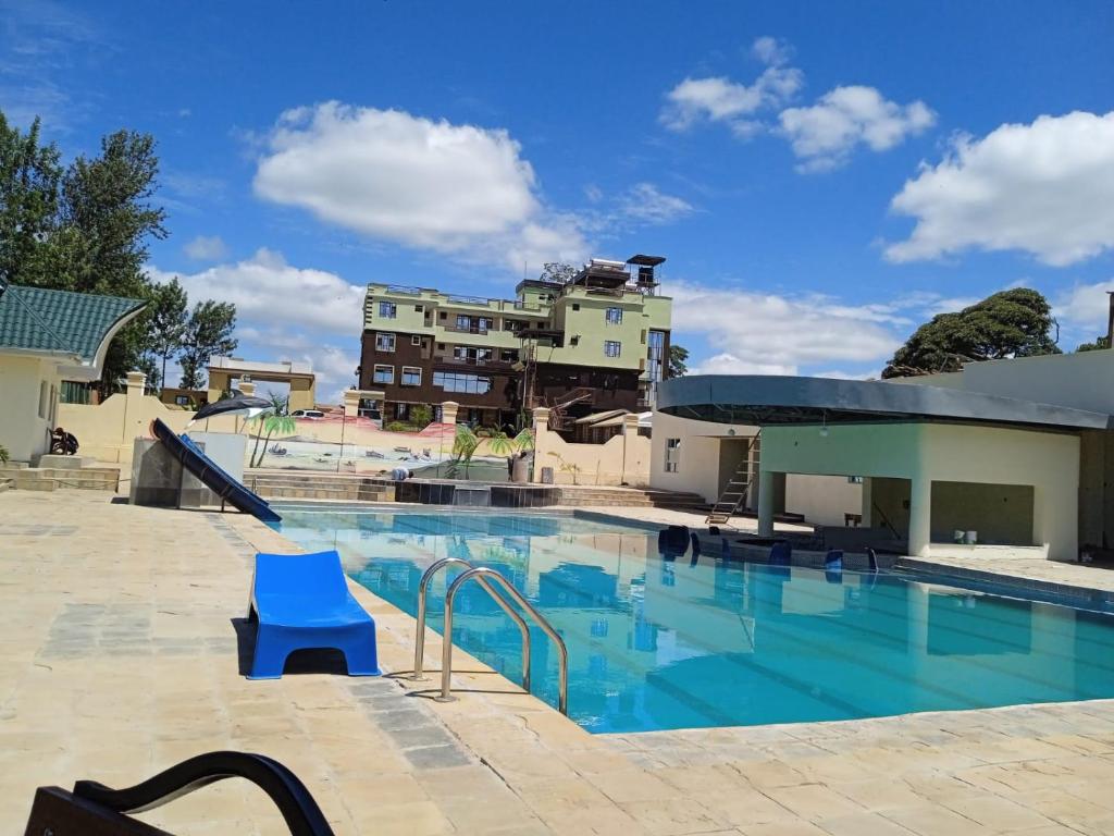 - une piscine avec une chaise bleue à côté d'un bâtiment dans l'établissement SILVER SLOPES RESORT AND SPA, à Kagio
