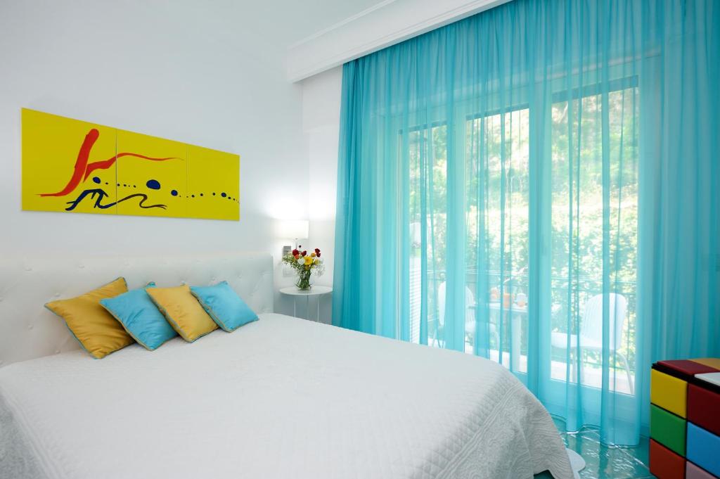 1 dormitorio con 1 cama con cortinas azules y ventana en Amalfia Apartments, en Amalfi