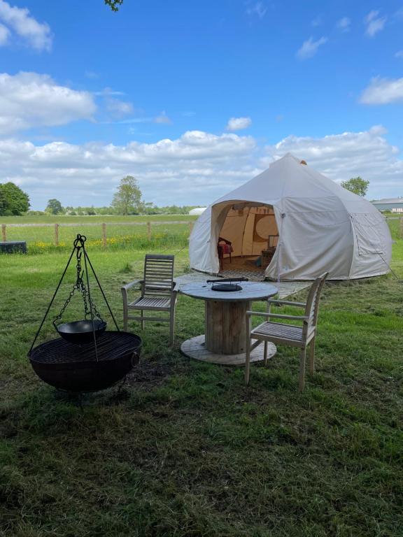 a tent and a table and chairs in a field at Nine Acres, peaceful in Brackley