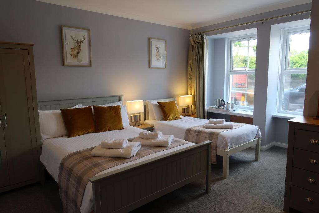 a bedroom with two beds and two windows at The Old Shop in Portree