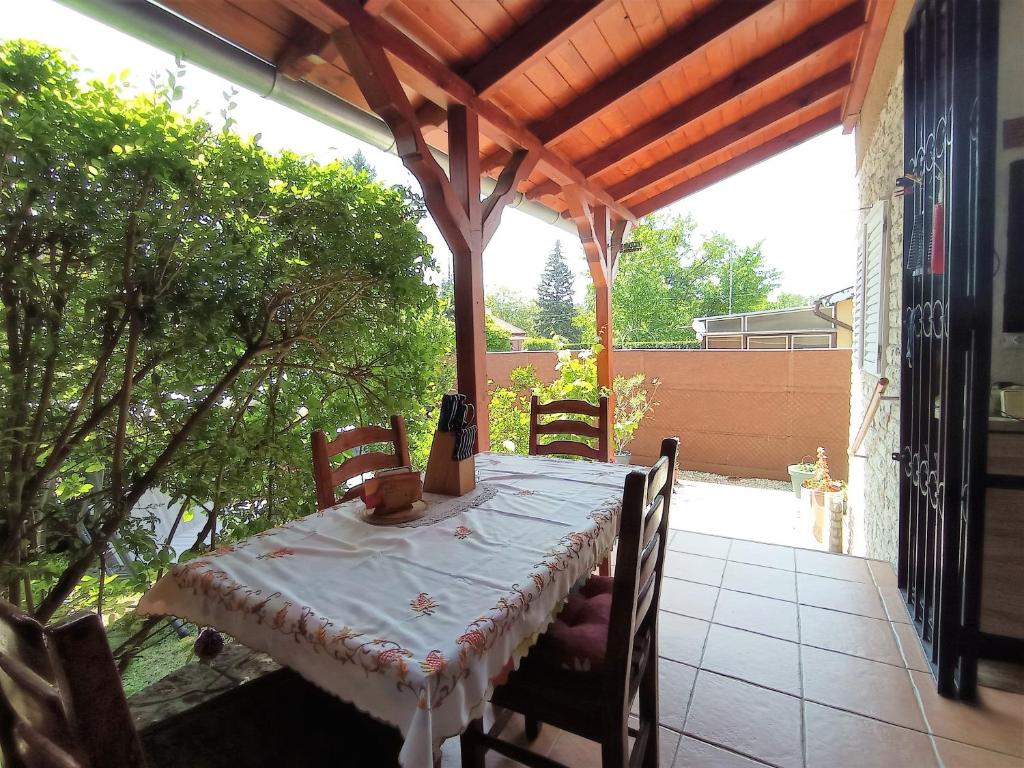 een tafel en stoelen op een patio met een dak bij Nosztalgia Apartman Balatonkenese in Balatonkenese