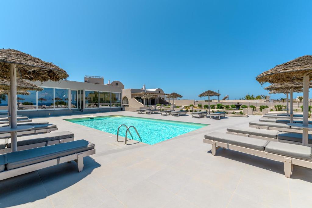 a swimming pool with benches and umbrellas at a resort at En Plo Boutique Suites in Oia