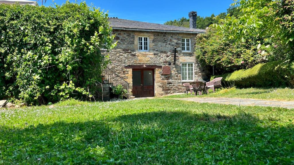 una casa de piedra con un banco delante en La Casa Antollosdocesar, en Baralla