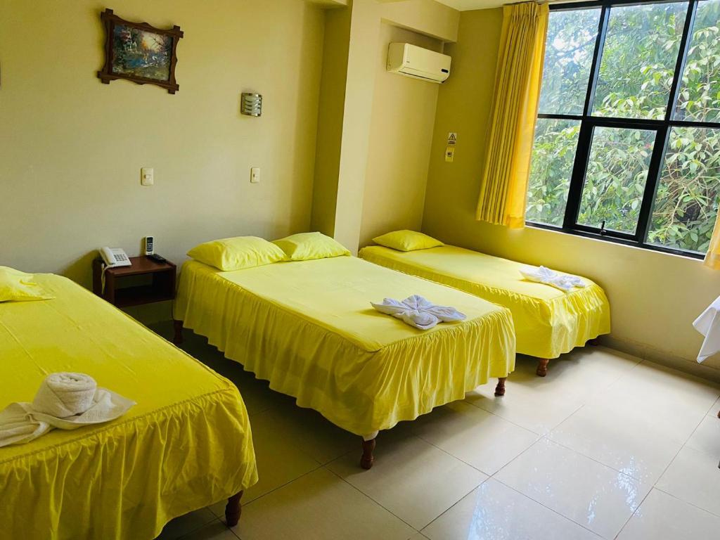 Habitación con 3 camas con sábanas amarillas. en Tahuari Hotel en Pucallpa