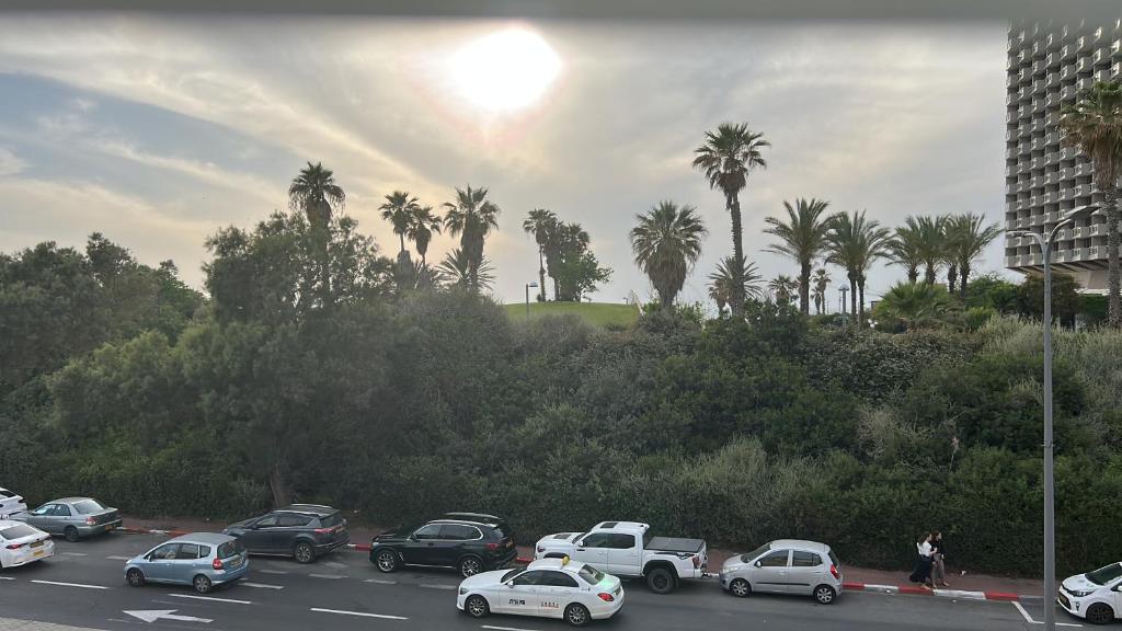 a parking lot filled with cars and palm trees at Apartment near Hilton in Tel Aviv