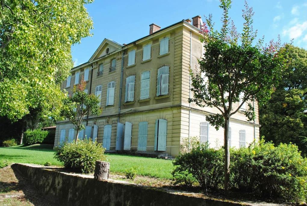 ein großes Haus mit blauen Fensterläden auf einem grünen Hof in der Unterkunft Château de Barral in Hauterives