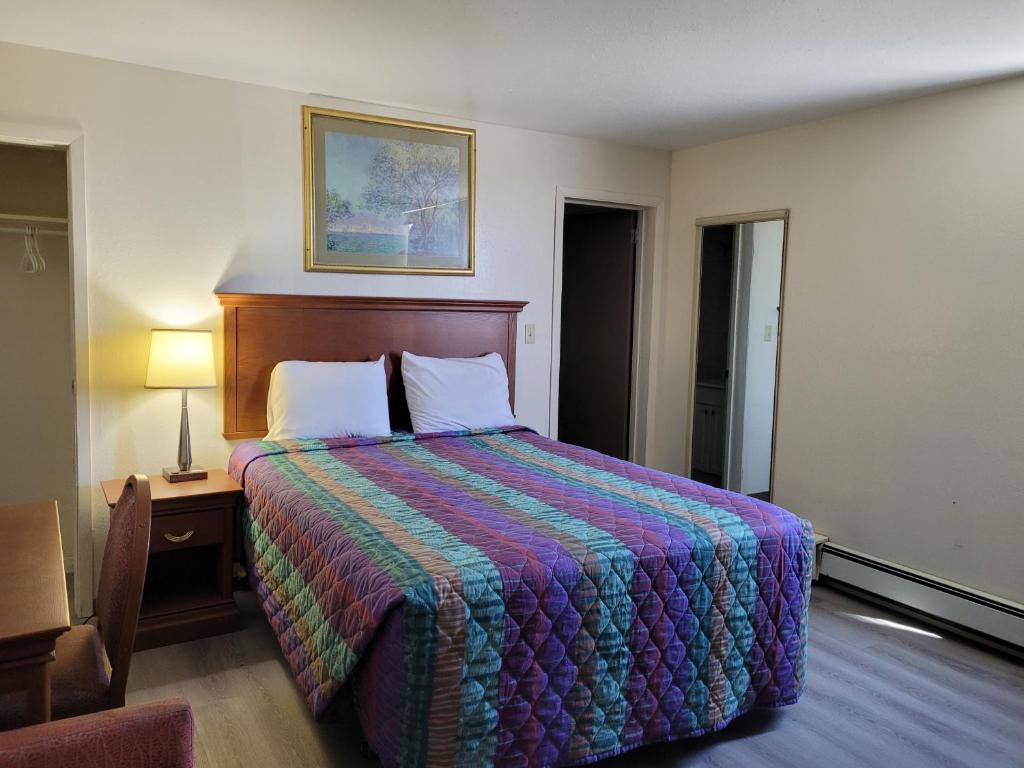 una habitación de hotel con una cama grande con una manta colorida en Canadiana Motel, en Sudbury