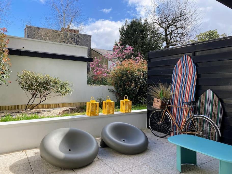 un patio con 2 taburetes, una tabla de surf y una mesa en Le Rosa Bonheur, en Nantes