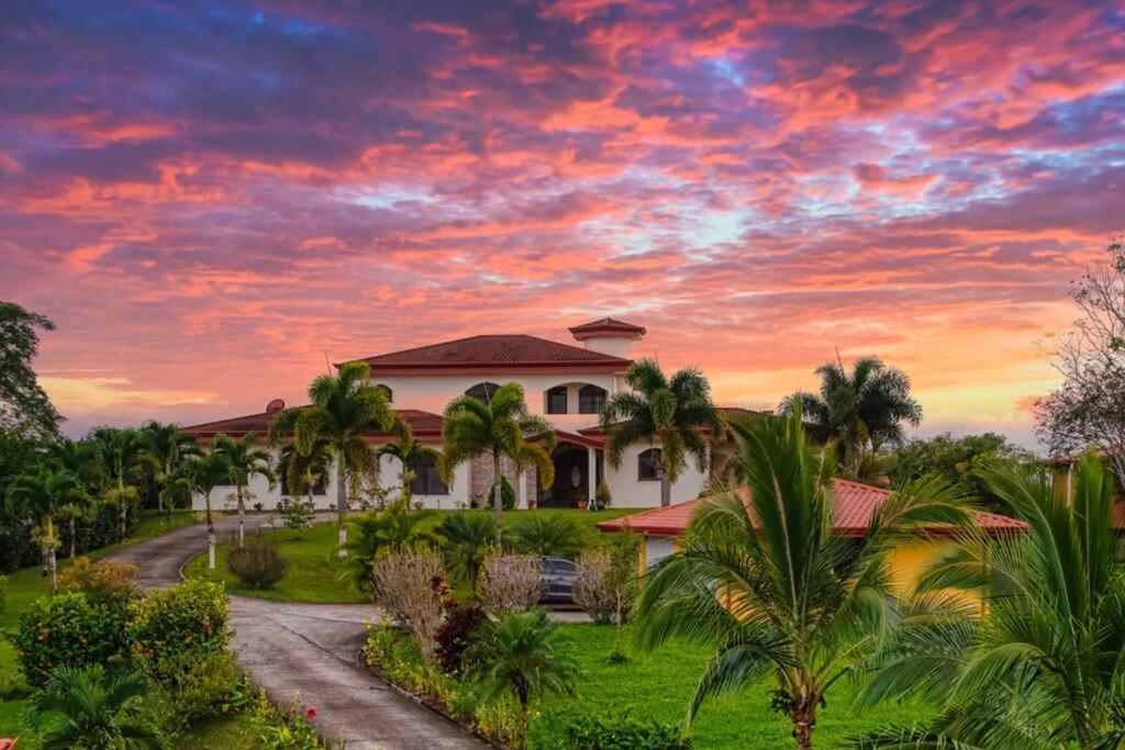 una casa con palmeras frente a la puesta de sol en Mountaintop Luxury Estate - Can Sleep up to 24!, en Macacona