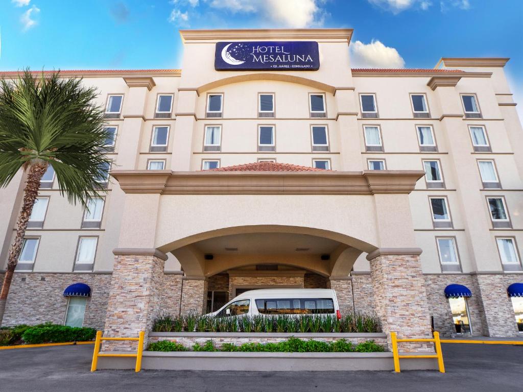 un hôtel situé en face d'un bâtiment avec un palmier dans l'établissement Hotel Mesaluna Near American Consulate, à Ciudad Juárez