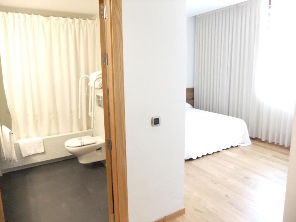 Un baño con una cama y un inodoro en una habitación. en Posada Miranda, en Miranda del Castañar