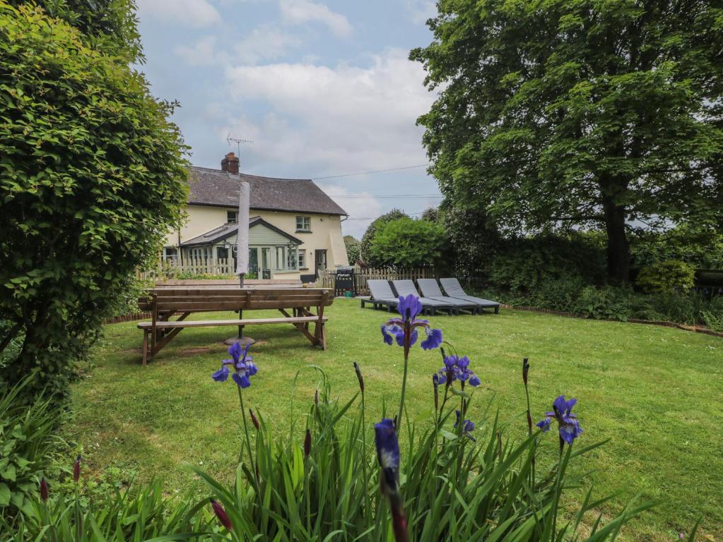 a picnic table and bench in a yard with flowers at 2 Pigsfoot Cottages in Tiverton