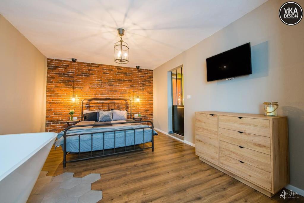 ein Schlafzimmer mit einem Bett und einer Ziegelwand in der Unterkunft Park Apartment 23 in Alba Iulia