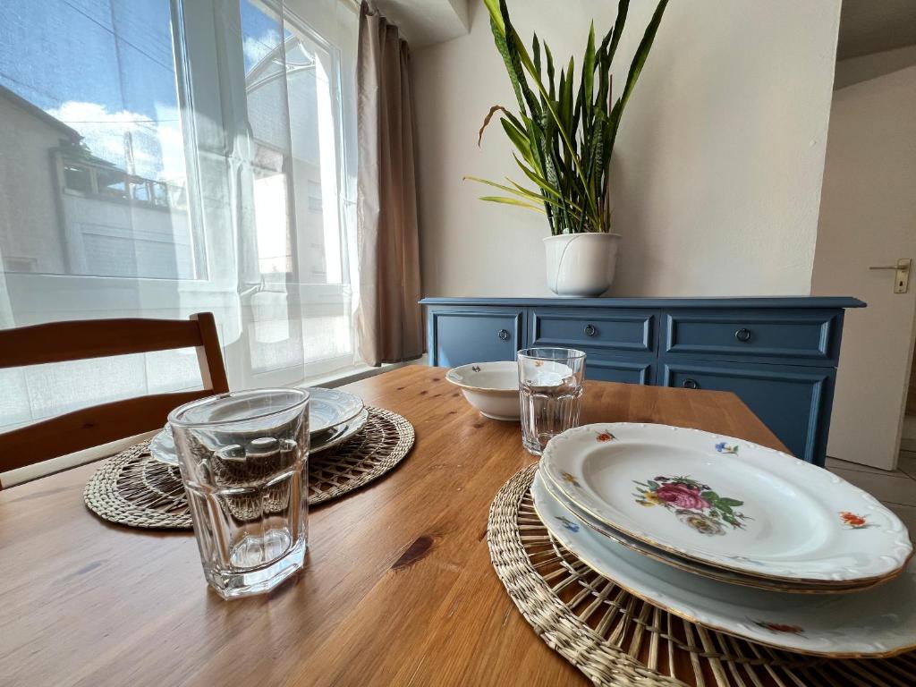 a wooden table with plates and glasses and a blue cabinet at Apartment Entenbrücke in Wendlingen am Neckar