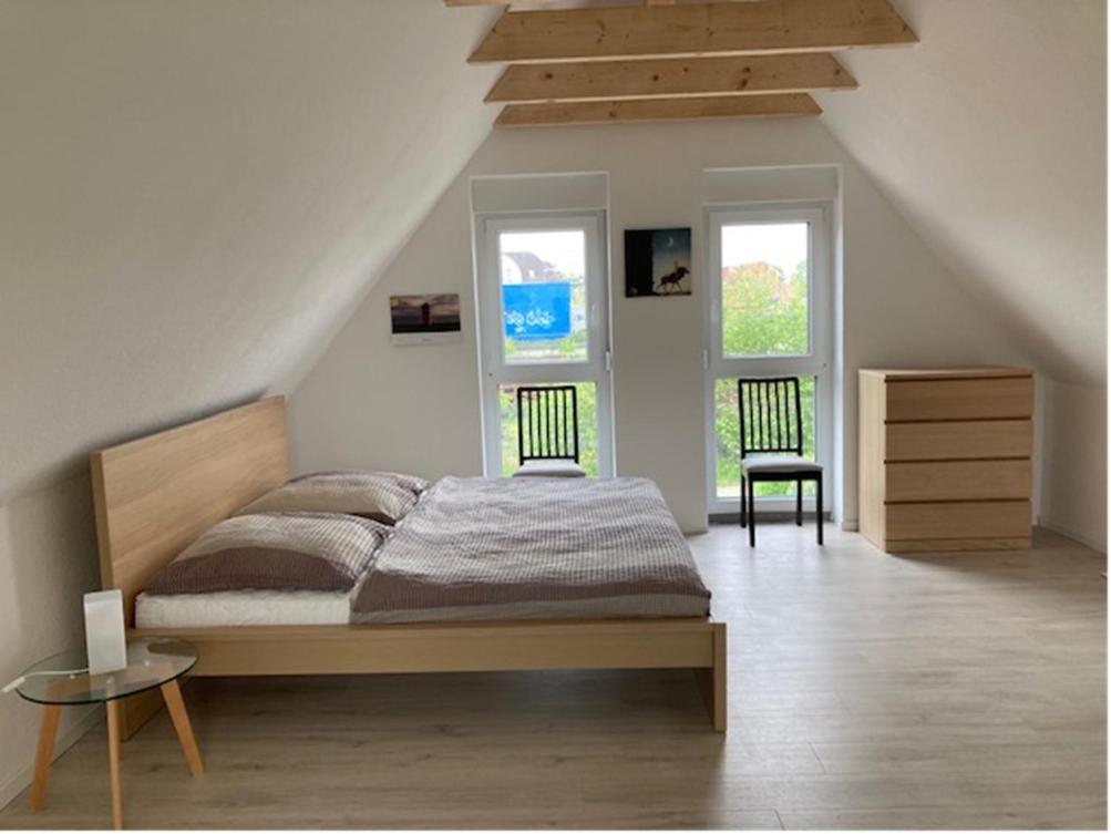 a bedroom with a bed and two chairs and two windows at Nordpier in Norden